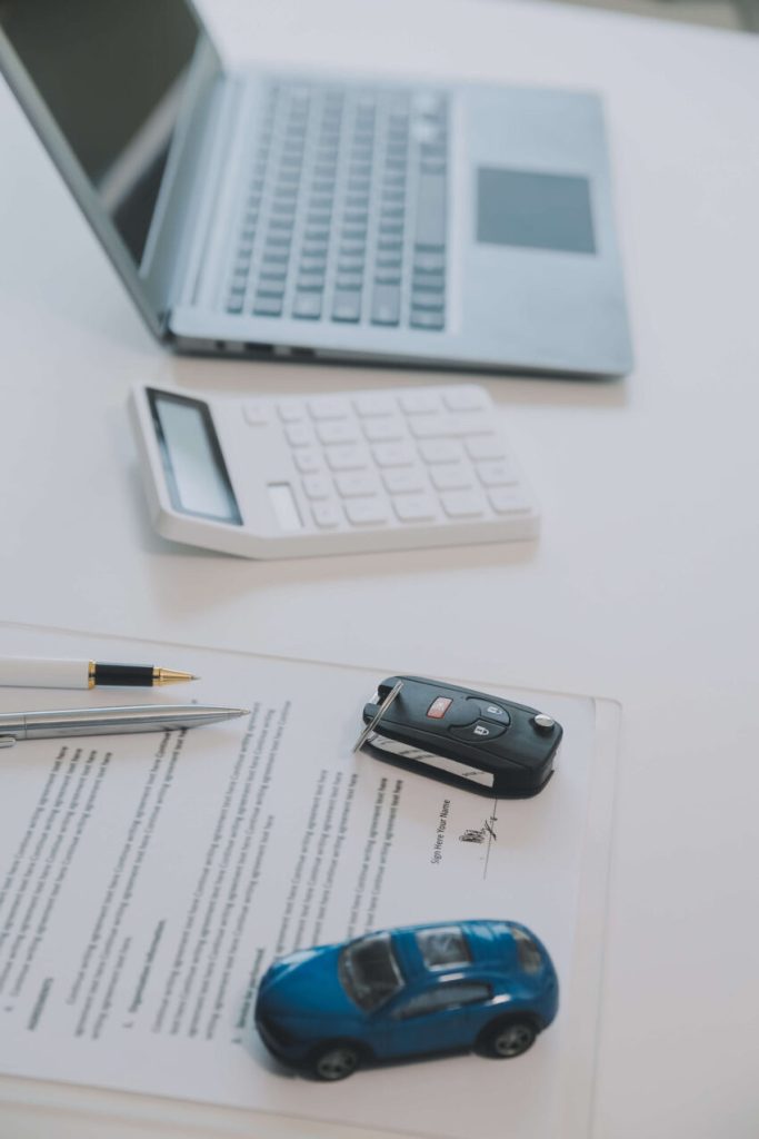Un'auto e un laptop posizionati su una scrivania, con un ambiente di lavoro moderno e ordinato.
